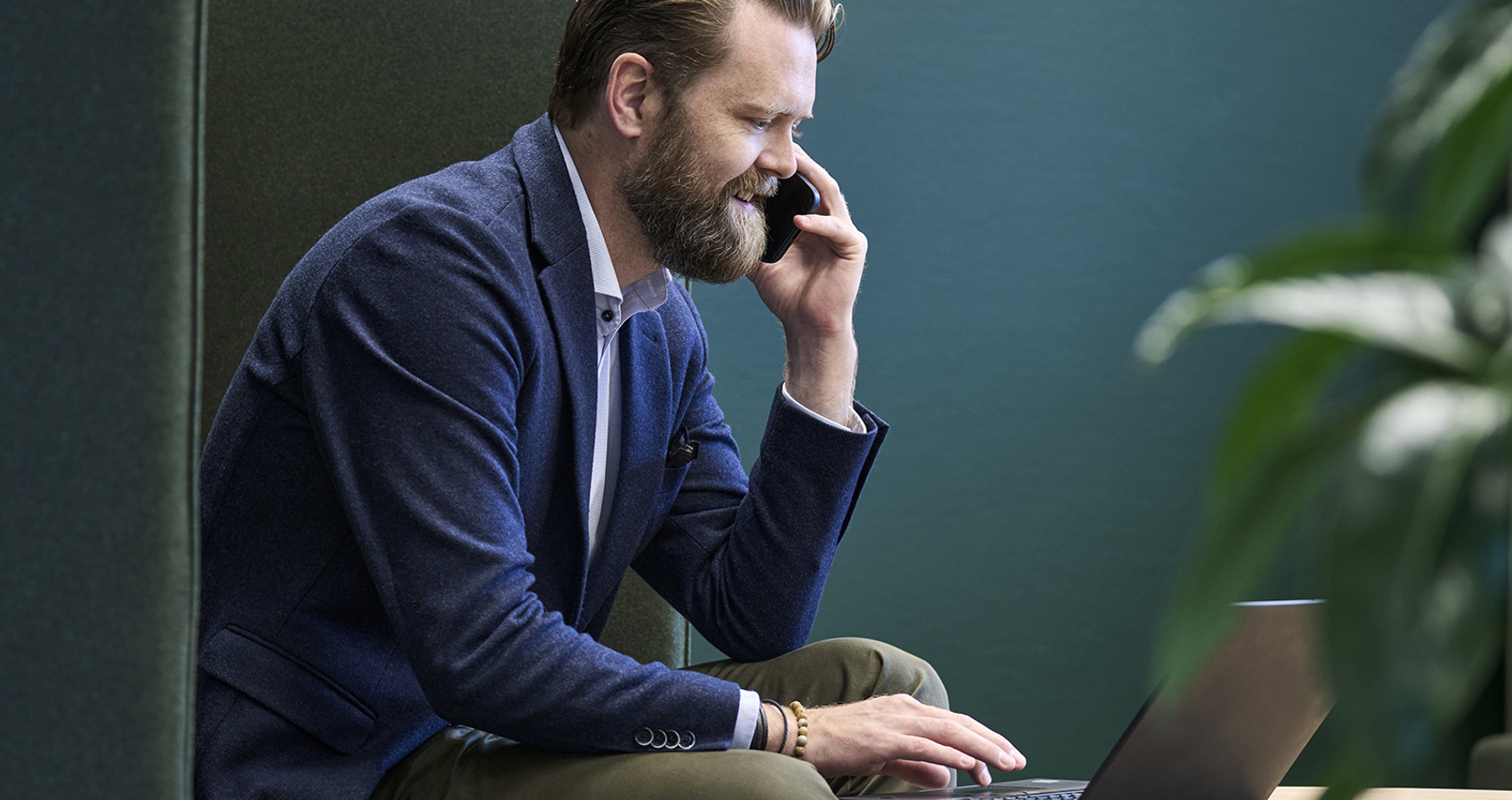 Kim Tovgaard, Head of Cloud & Modern Workplace, i et telefonopkald mens han bruger sin laptop på et lille rundt bord
